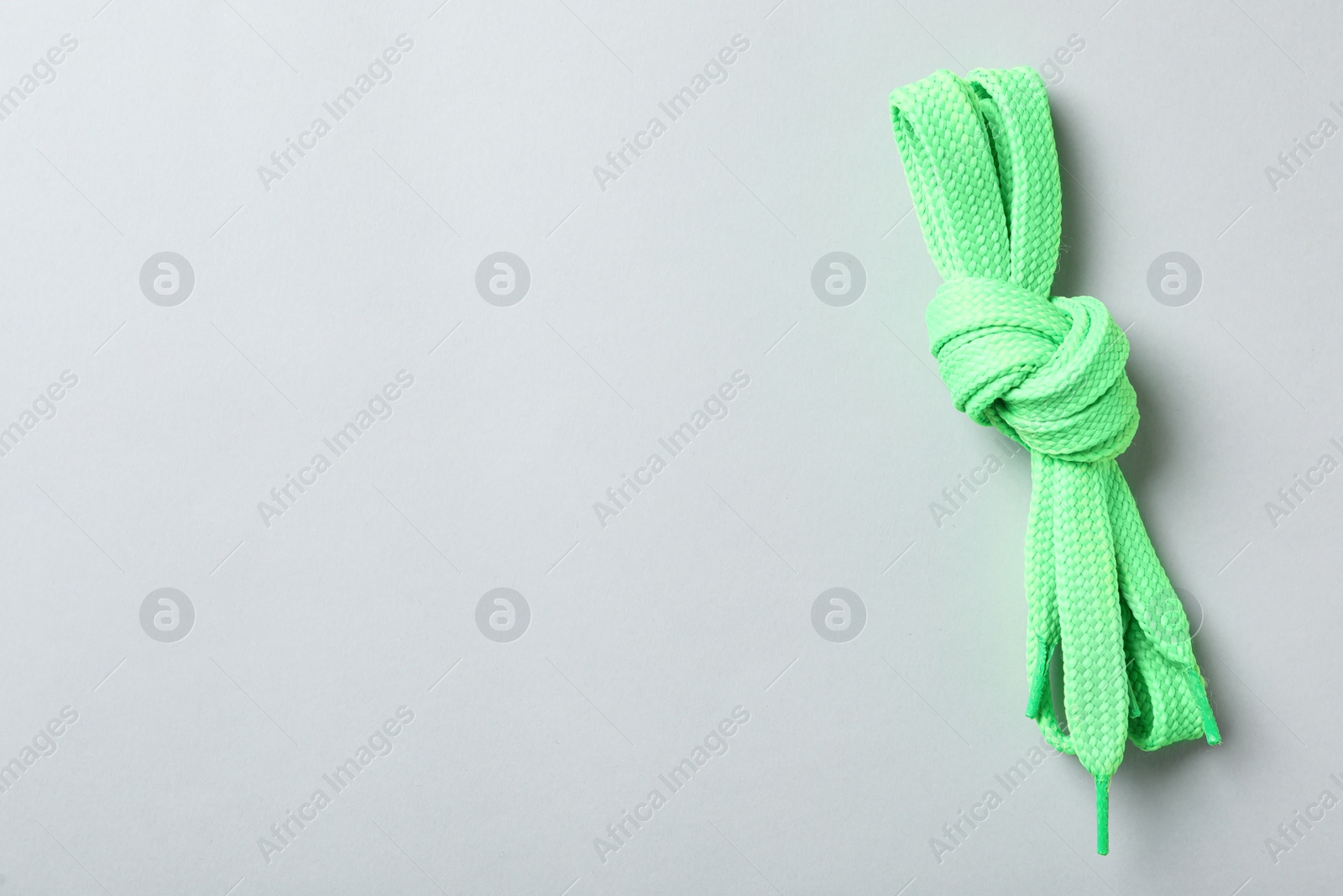 Photo of Green shoelaces on light background, top view. Space for text