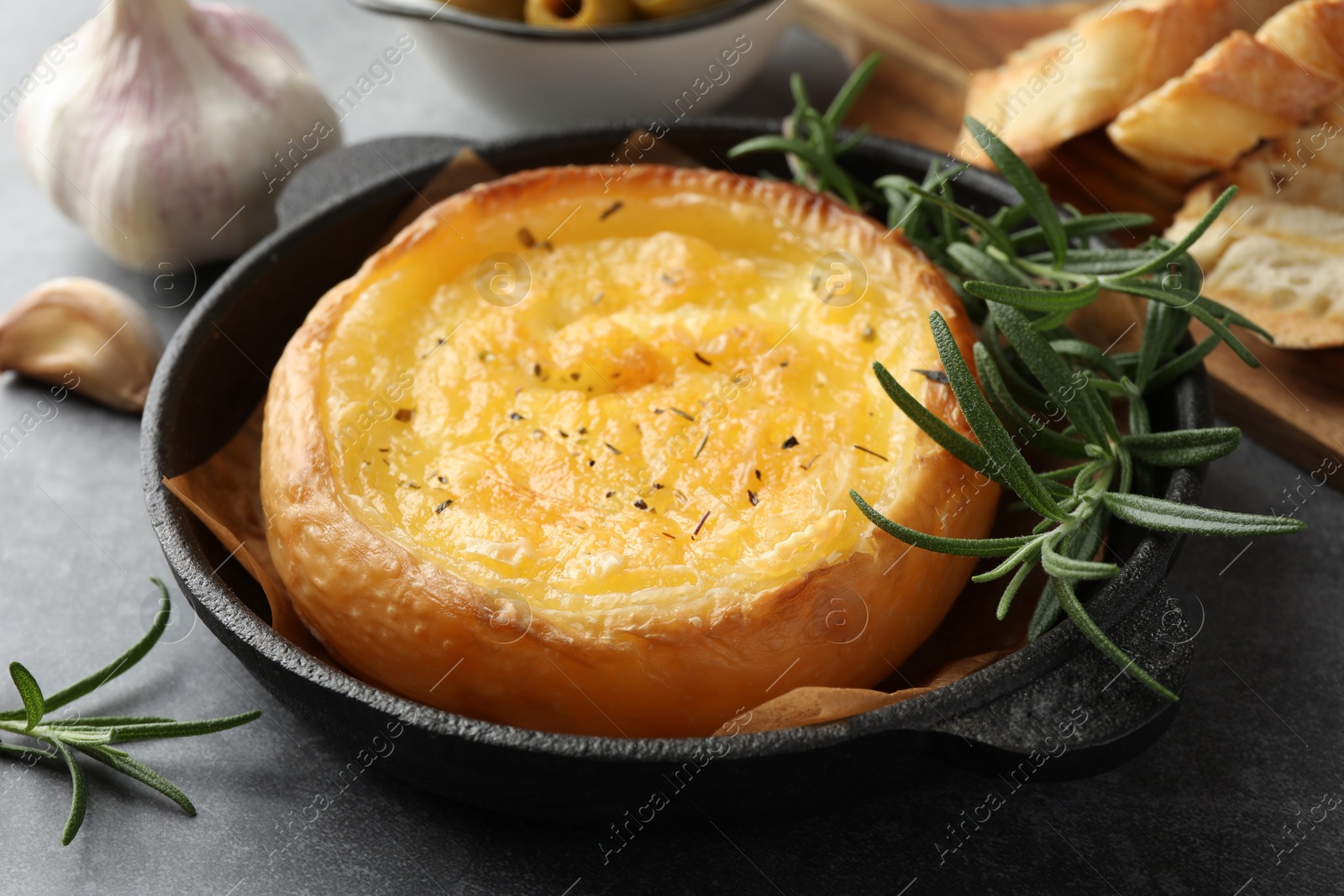 Photo of Tasty baked brie cheese and rosemary on grey table, closeup