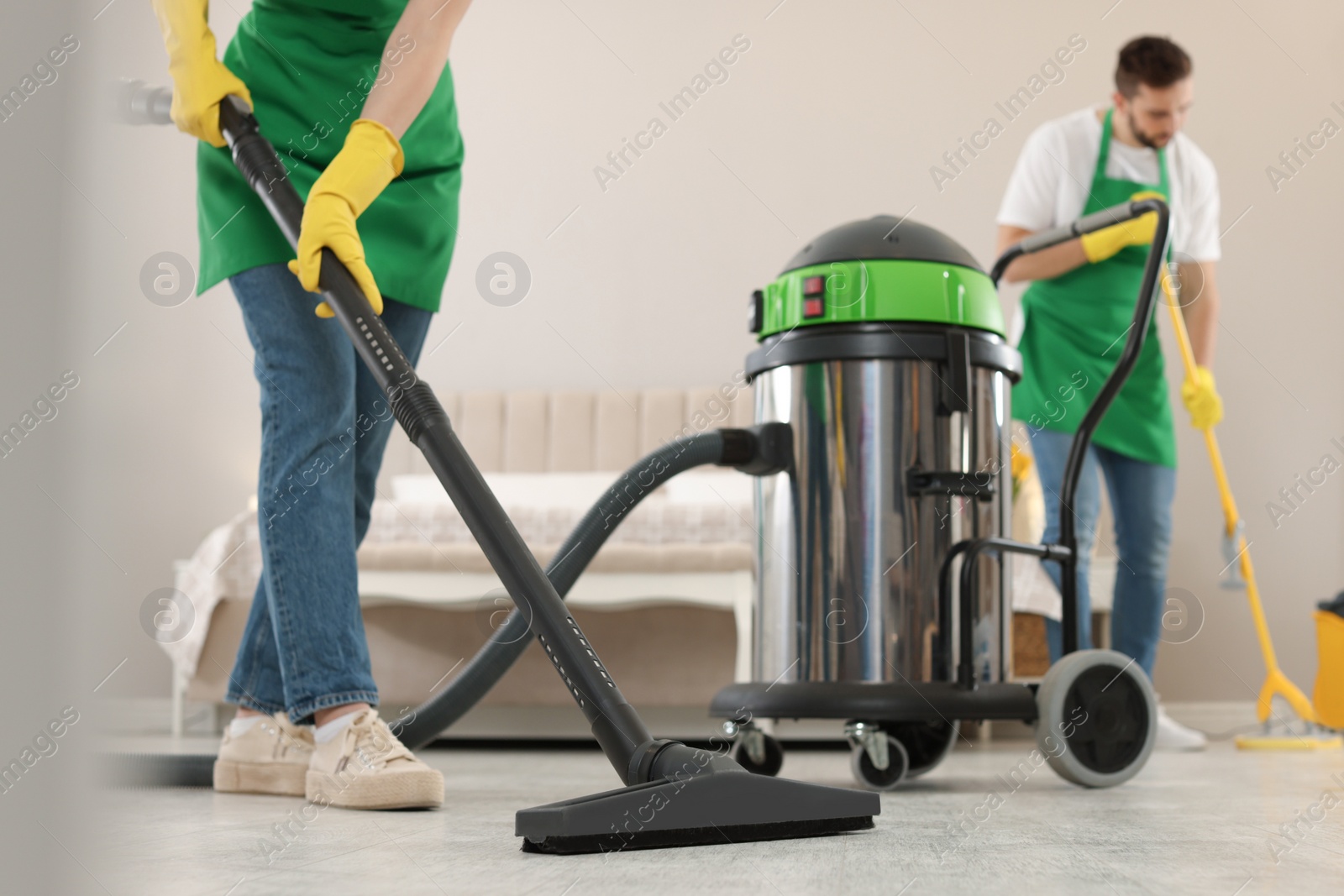 Photo of Professional janitors working in bedroom, closeup. Cleaning service