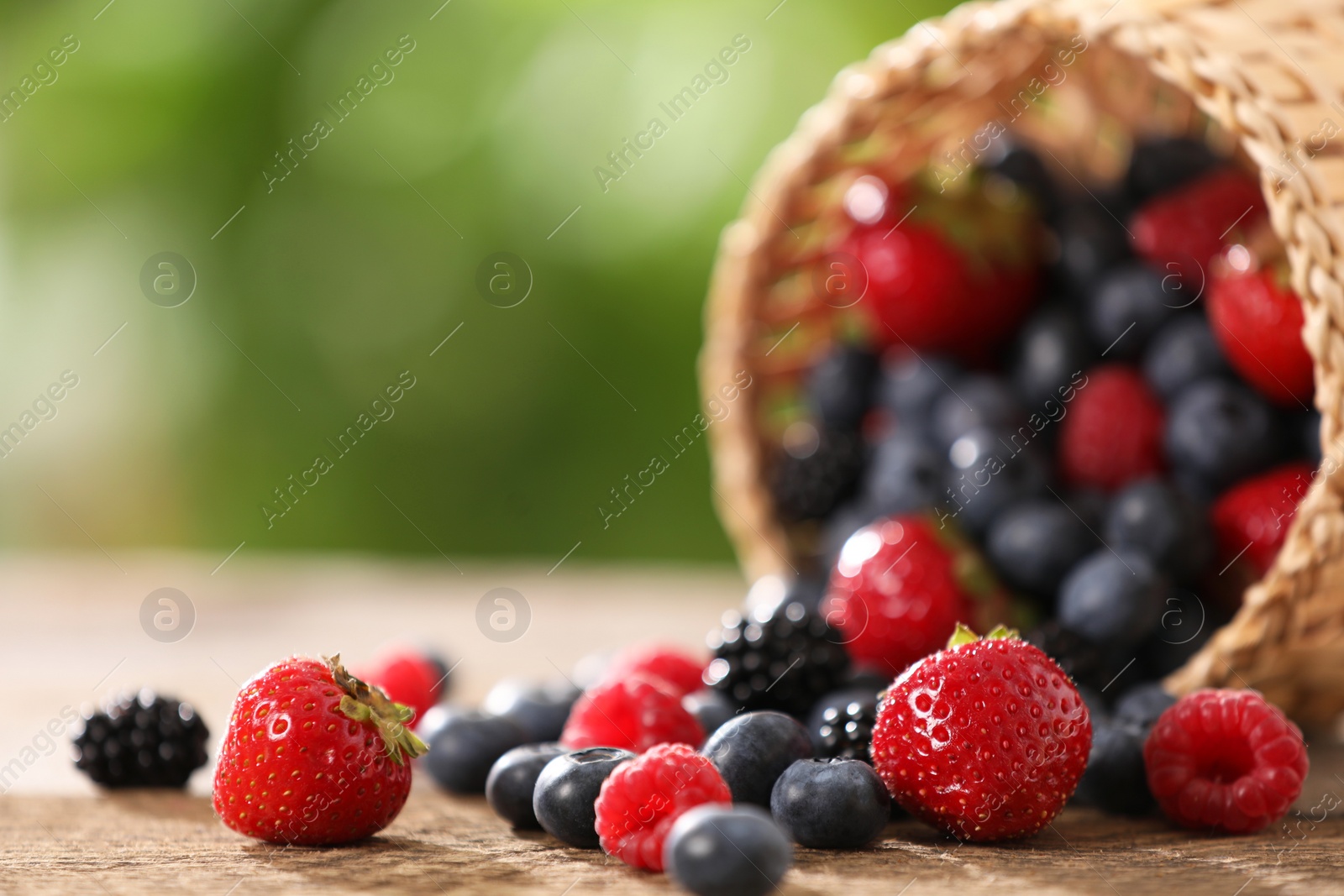 Photo of Different fresh ripe berries on wooden table outdoors, closeup