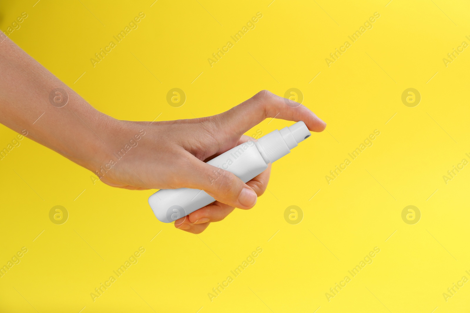 Photo of Woman with bottle of insect repellent spray on yellow background, closeup