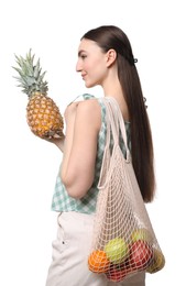 Photo of Woman with string bag of fresh fruits holding pineapple on white background