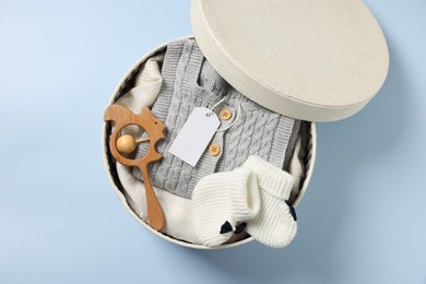 Photo of Different baby accessories and clothes in box on light blue background, top view