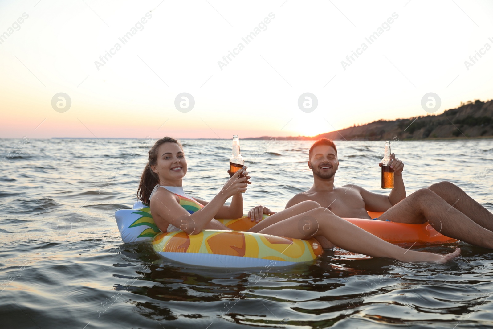 Photo of Happy young couple on inflatable rings in water