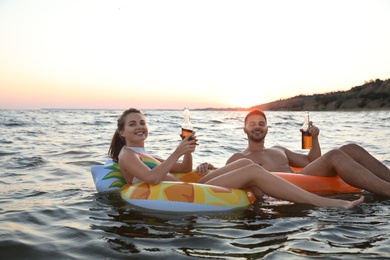 Photo of Happy young couple on inflatable rings in water