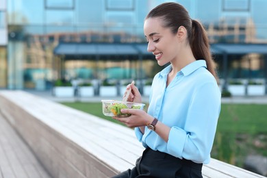 Photo of Smiling businesswoman eating lunch outdoors. Space for text