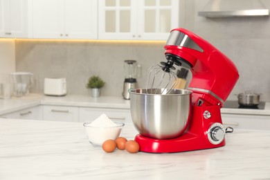 Modern red stand mixer, eggs and bowl with flour on white marble table in kitchen, space for text