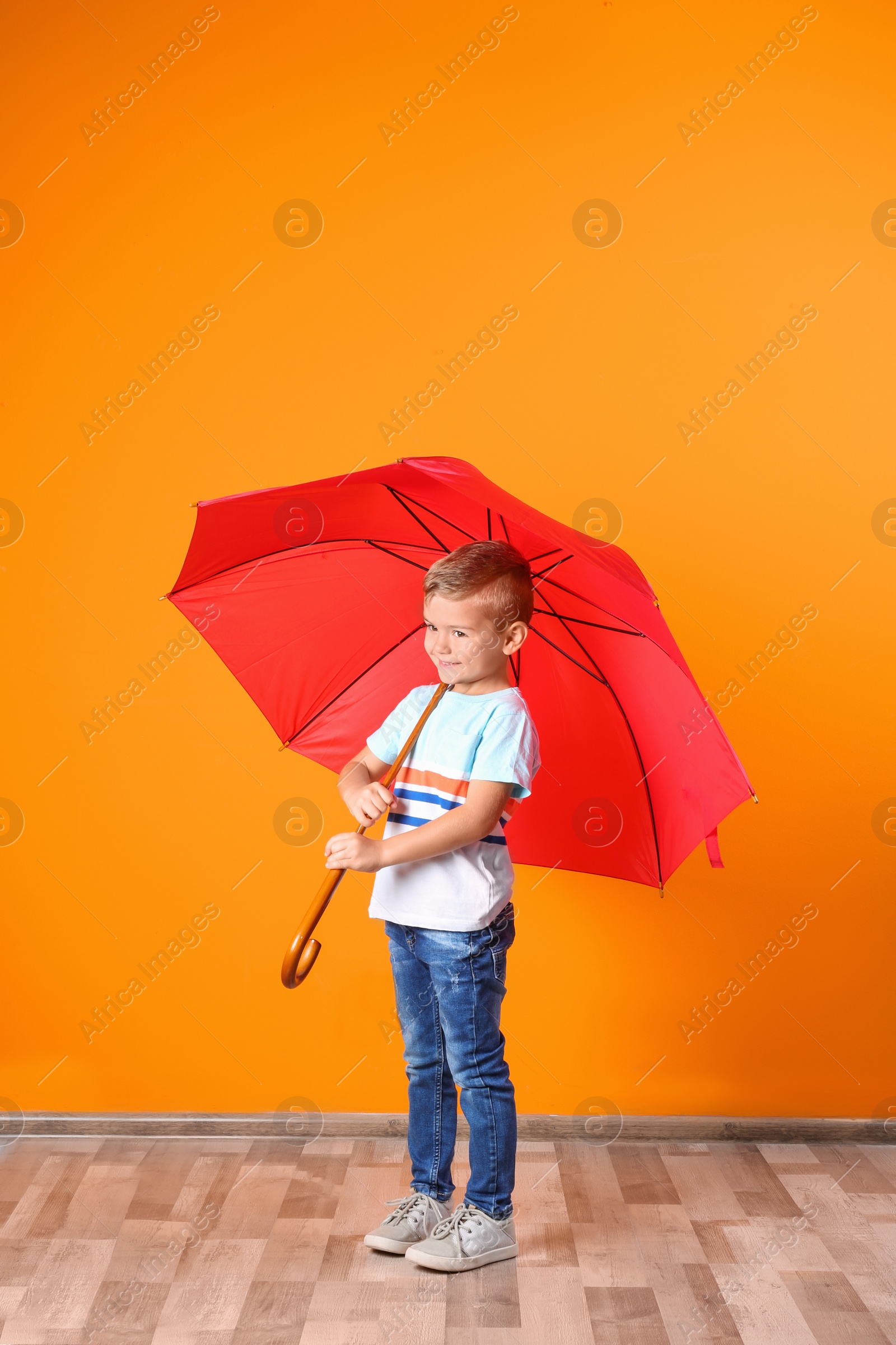 Photo of Little boy with red umbrella near color wall