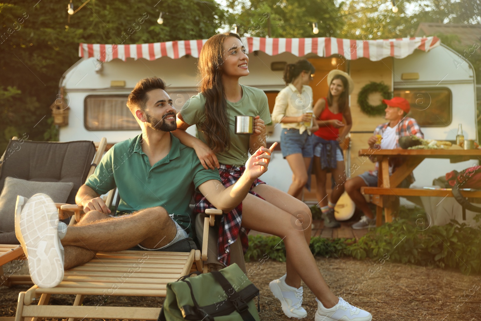 Photo of Happy friends resting near motorhome. Camping season