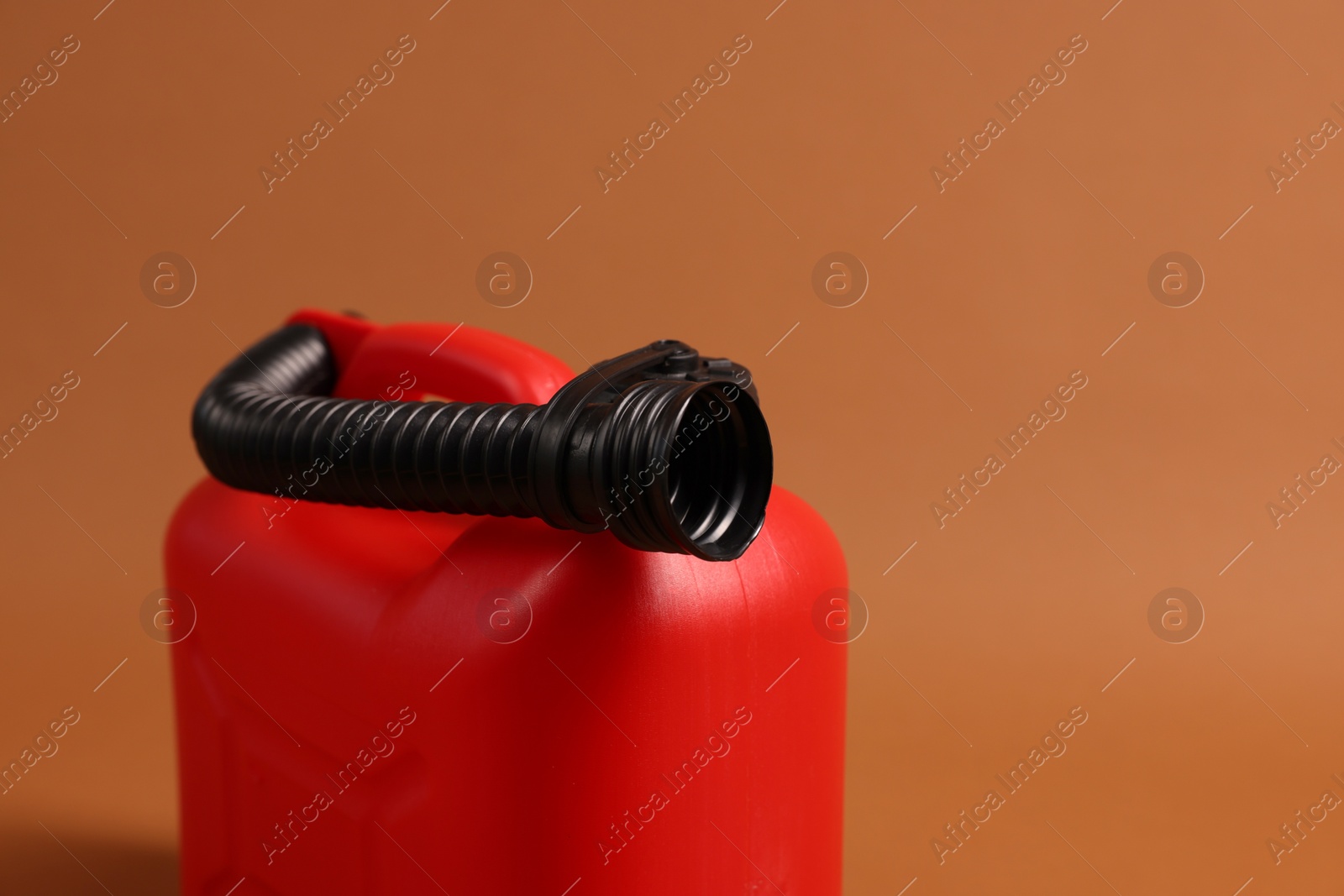 Photo of New red plastic canister on brown background, closeup. Space for text