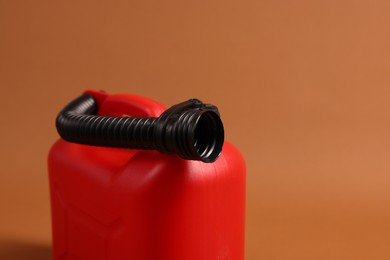 New red plastic canister on brown background, closeup. Space for text