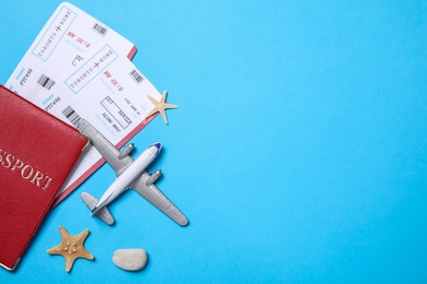 Photo of Toy airplane, passport with tickets and seashells on light blue background, flat lay. Space for text