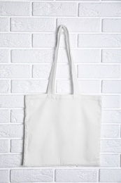 Photo of Tote bag hanging on brick wall. Mock up for design