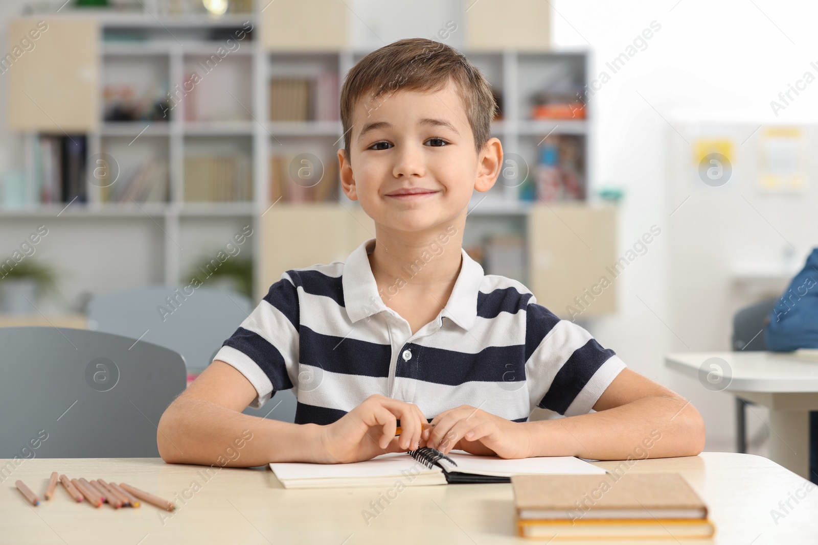 Photo of Portrait of cute little boy studying in classroom at school