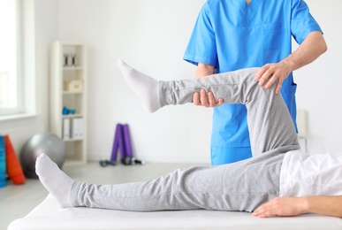 Photo of Physiotherapist working with male patient in clinic