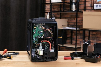 Photo of Broken coffee machine on wooden table indoors