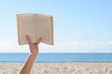 Photo of Woman reading book on beach near sea, closeup. Space for text