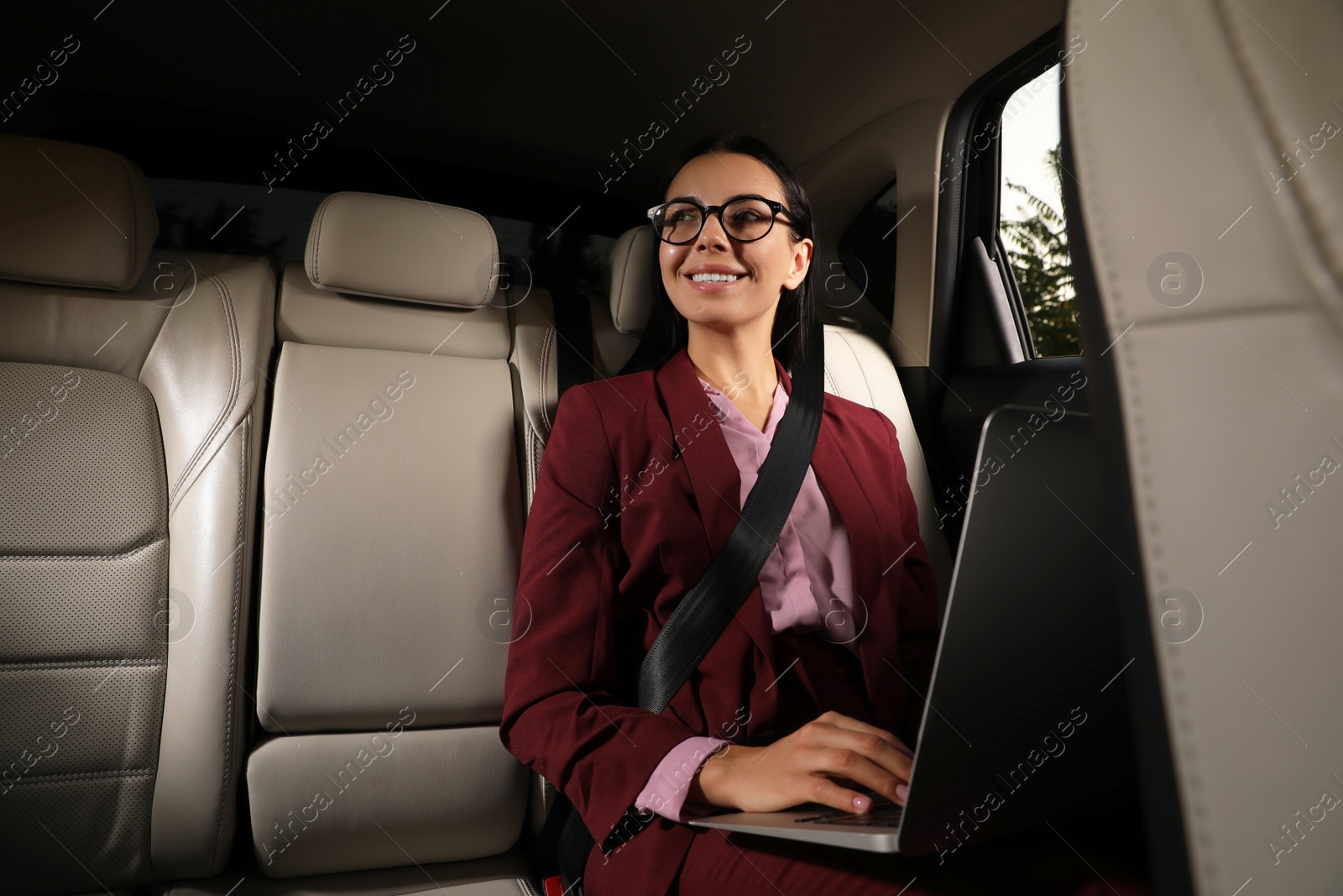 Photo of Young woman working on laptop in modern taxi, space for text