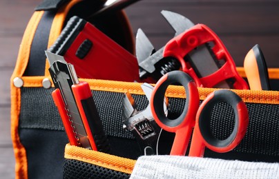Photo of Bag with utility knife and different tools, closeup