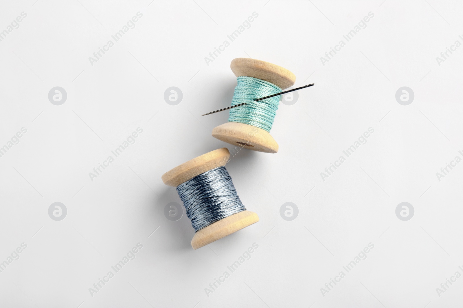 Photo of Colorful sewing threads with needle on white background, top view