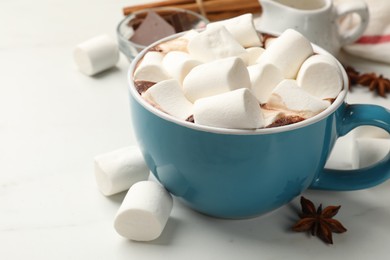 Photo of Tasty hot chocolate with marshmallows and ingredients on white table, closeup. Space for text