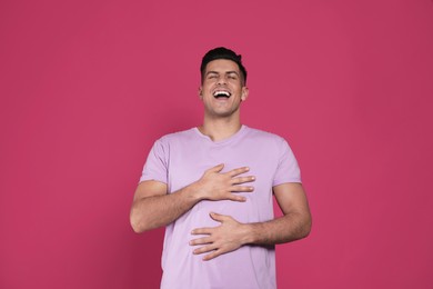 Handsome man laughing on maroon background. Funny joke