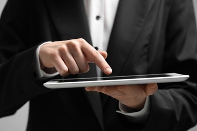 Closeup view of woman using modern tablet on grey background