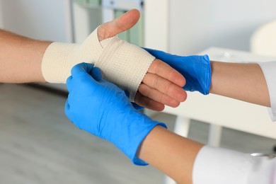 Photo of Doctor applying medical bandage onto patient's hand in hospital, closeup