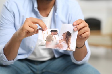 Photo of Man tearing photo indoors, closeup. Divorce concept