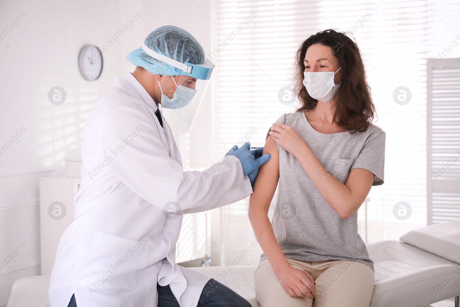 Photo of Doctor vaccinating mature woman against Covid-19 in clinic