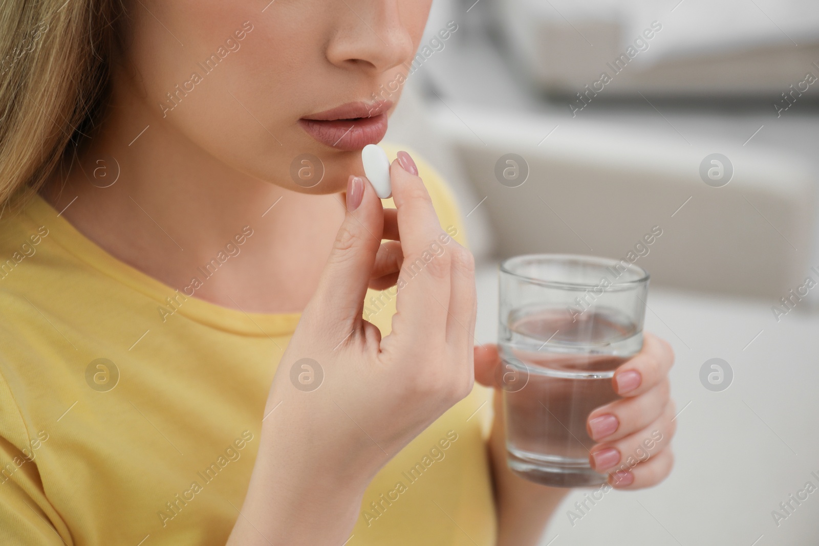 Photo of Young woman taking abortion pill on blurred background, closeup