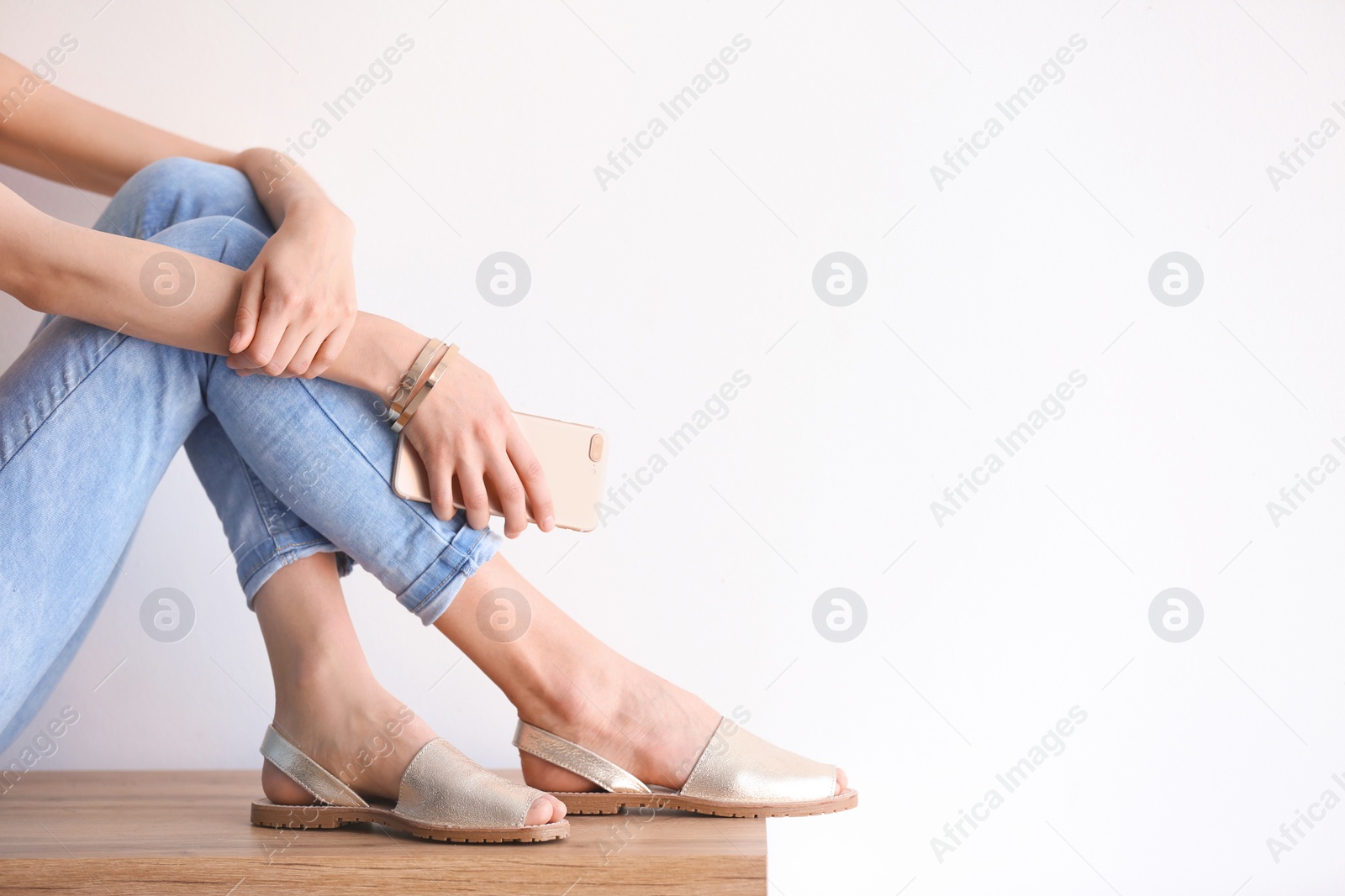 Photo of Young woman in elegant shoes sitting on table, closeup