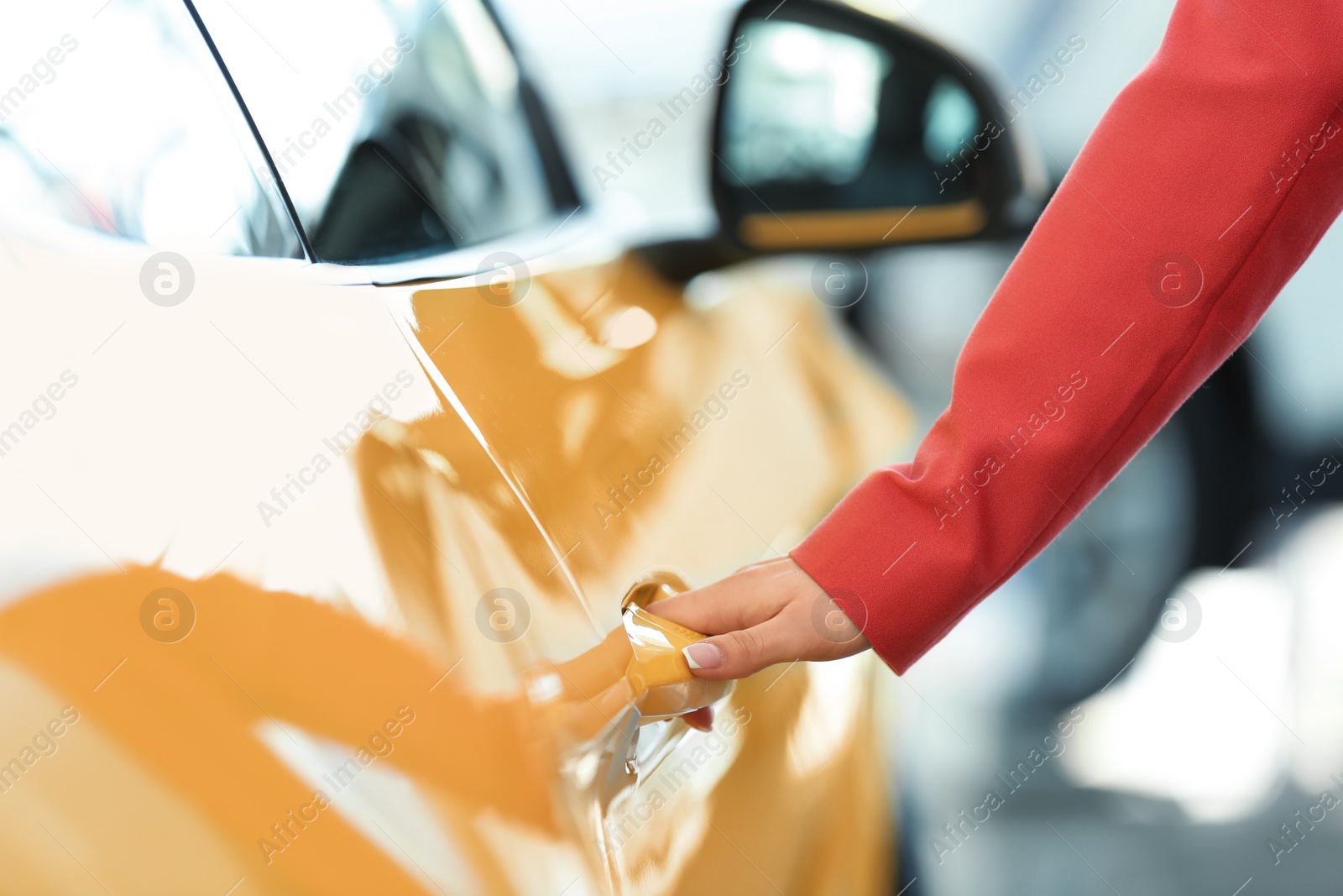 Photo of Young woman opening door of new car, closeup