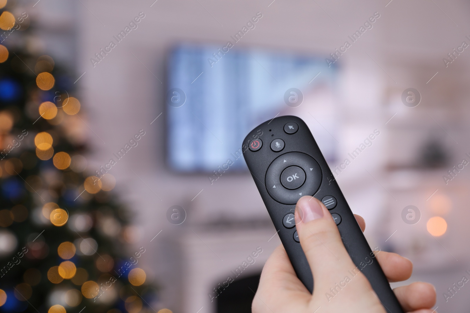 Photo of Woman with remote control watching TV at home, closeup. Space for text