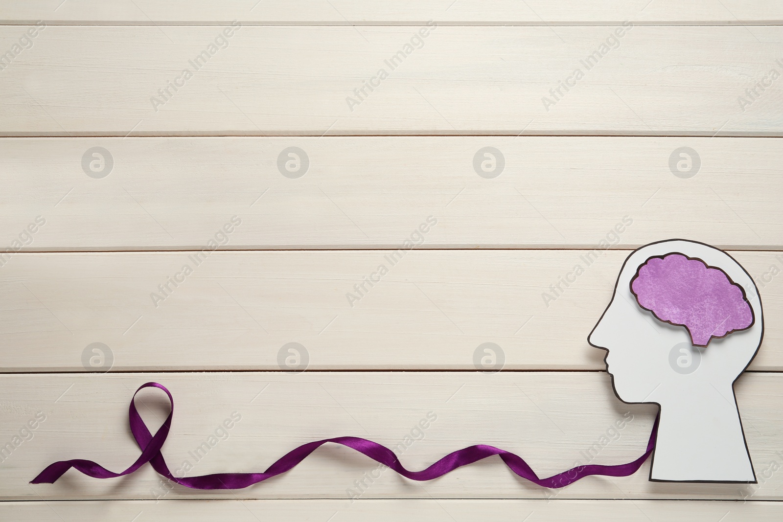 Photo of Human head cutout, brain and purple ribbon on white wooden background, flat lay with space for text. Epilepsy awareness