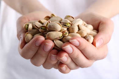 Photo of Woman holding handful of tasty pistachios, closeup