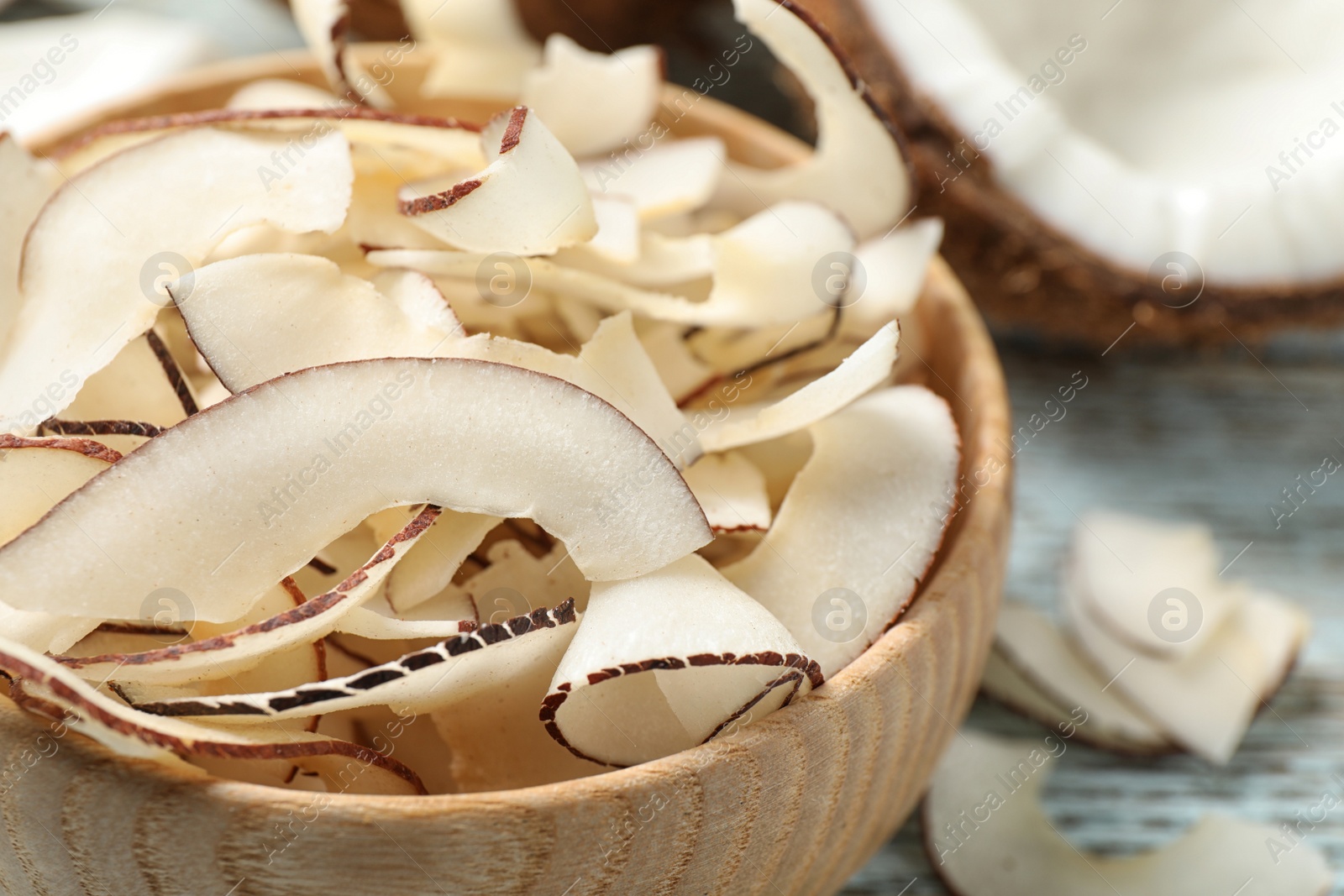 Photo of Tasty coconut chips in wooden bowl, closeup