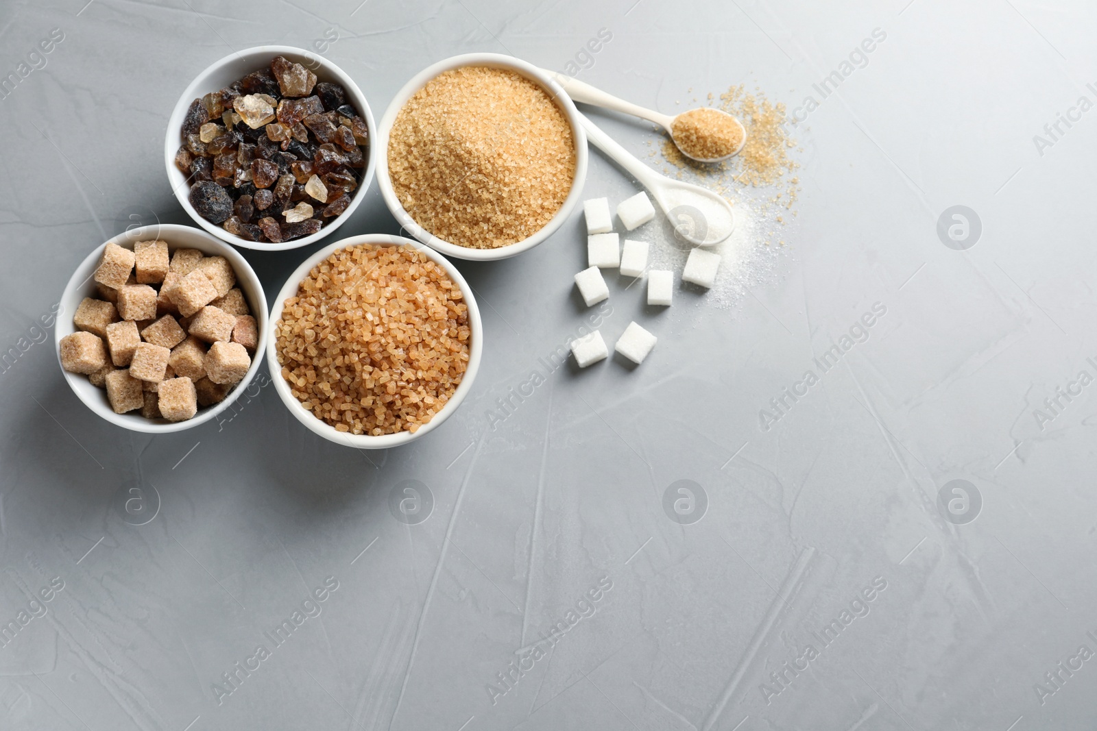 Photo of Flat lay composition with different types of sugar on gray background