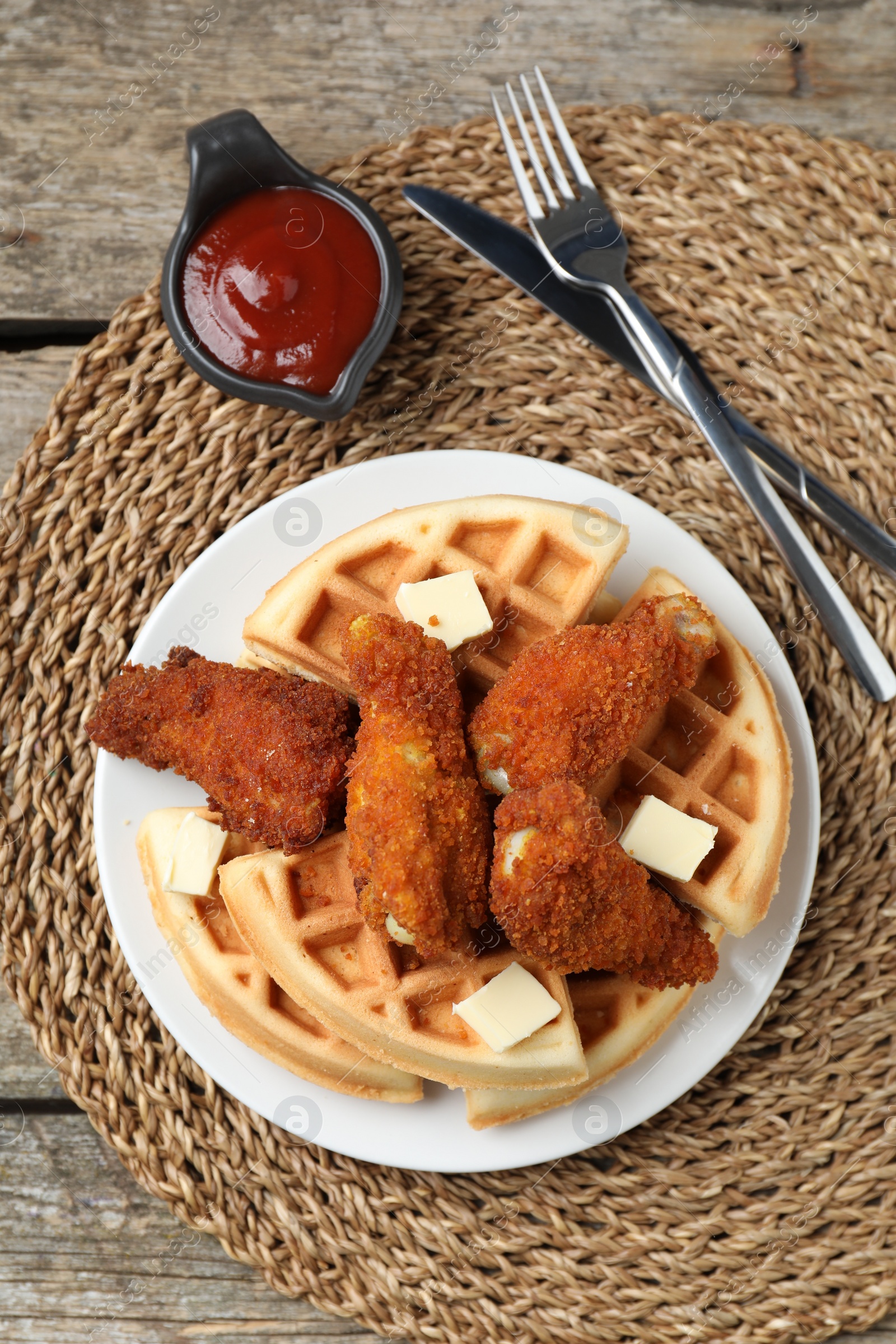 Photo of Delicious Belgium waffles served with fried chicken and butter on wooden table, top view