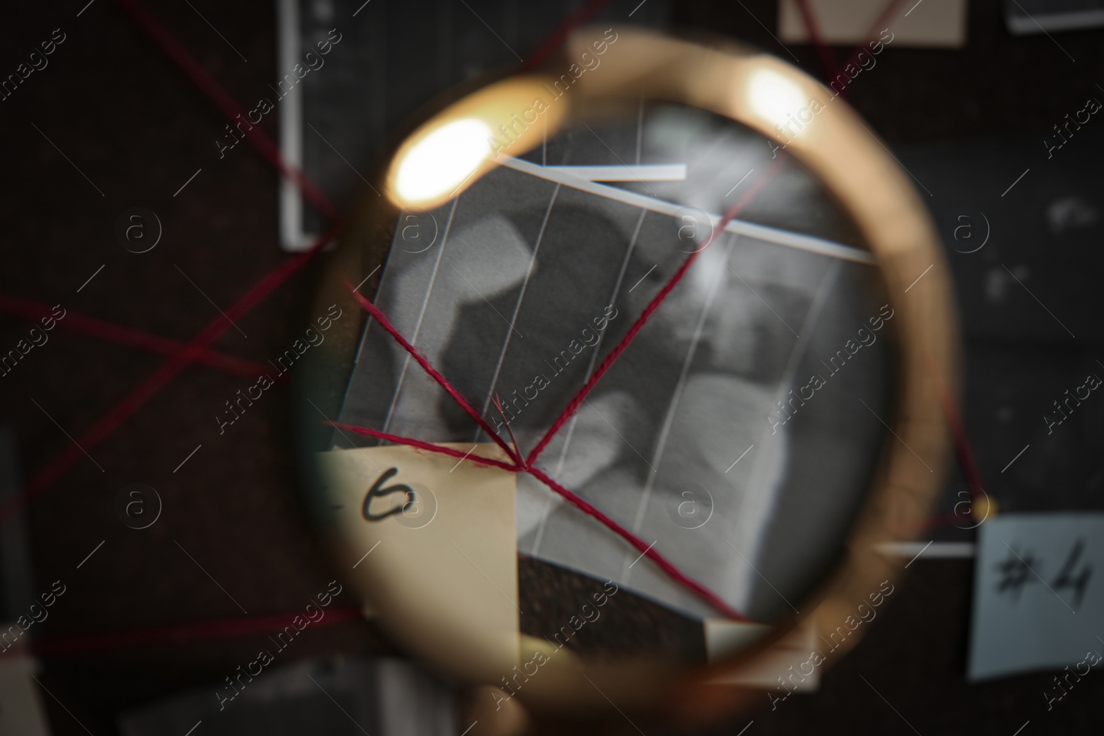 Photo of Looking at detective board through magnifying glass, closeup