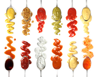Image of Set of spoons with different delicious sauces on white background, top view