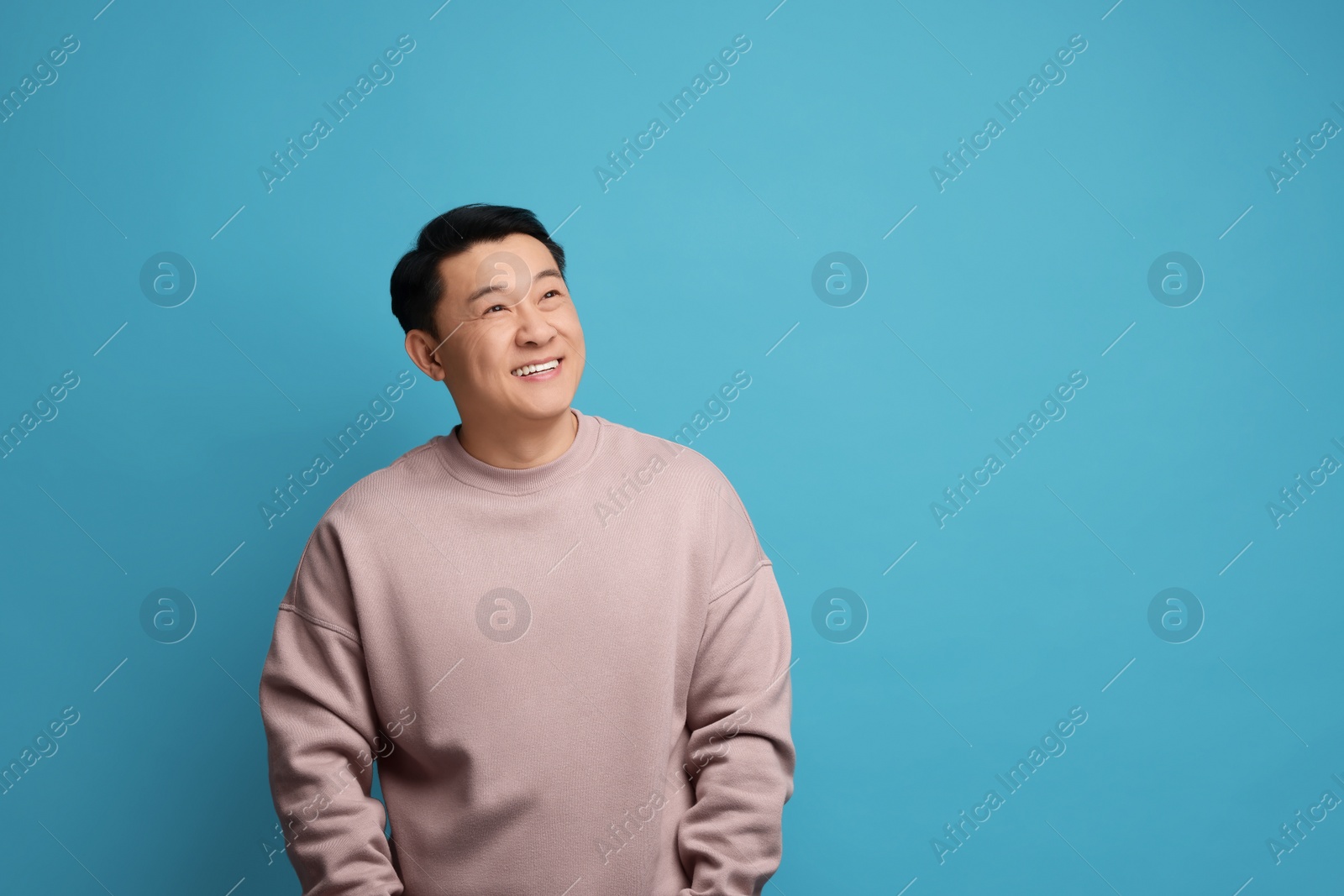 Photo of Portrait of happy man on light blue background. Space for text