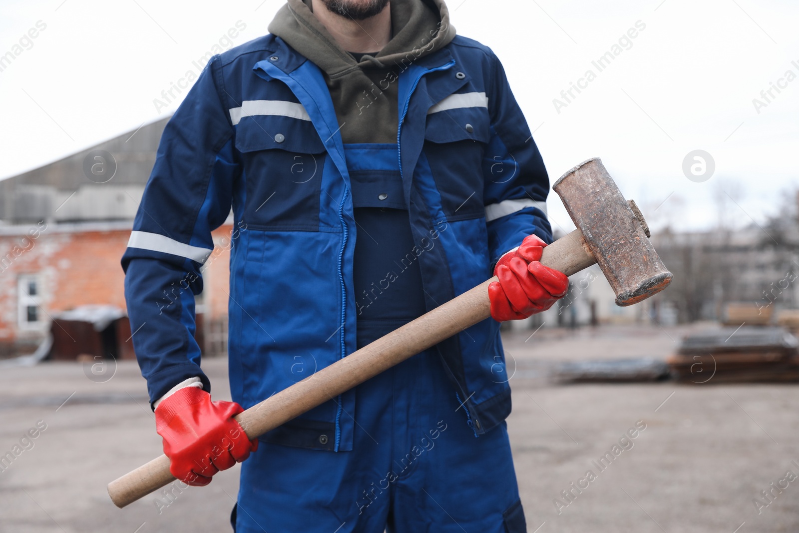 Photo of Man in uniform with sledgehammer outdoors, closeup