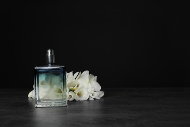 Photo of Perfume bottle and flowers on table against black background