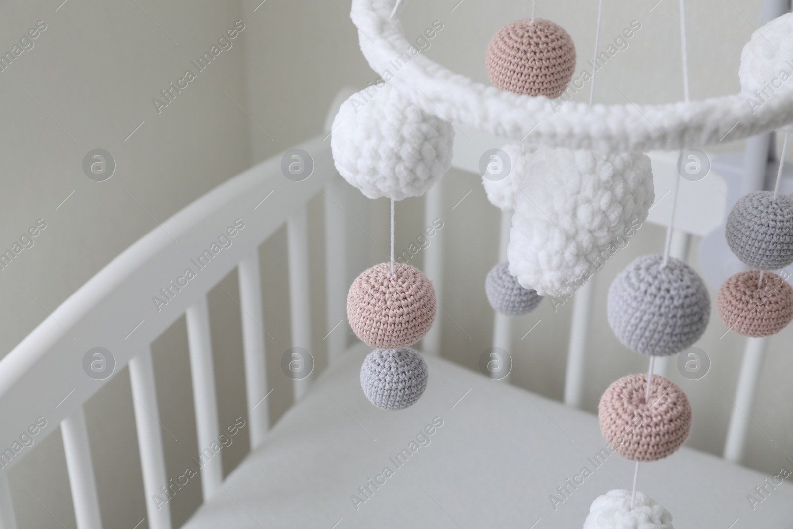 Photo of Modern baby mobile under crib in children's room, closeup