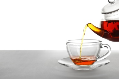 Photo of Pouring hot tea into glass cup on white background