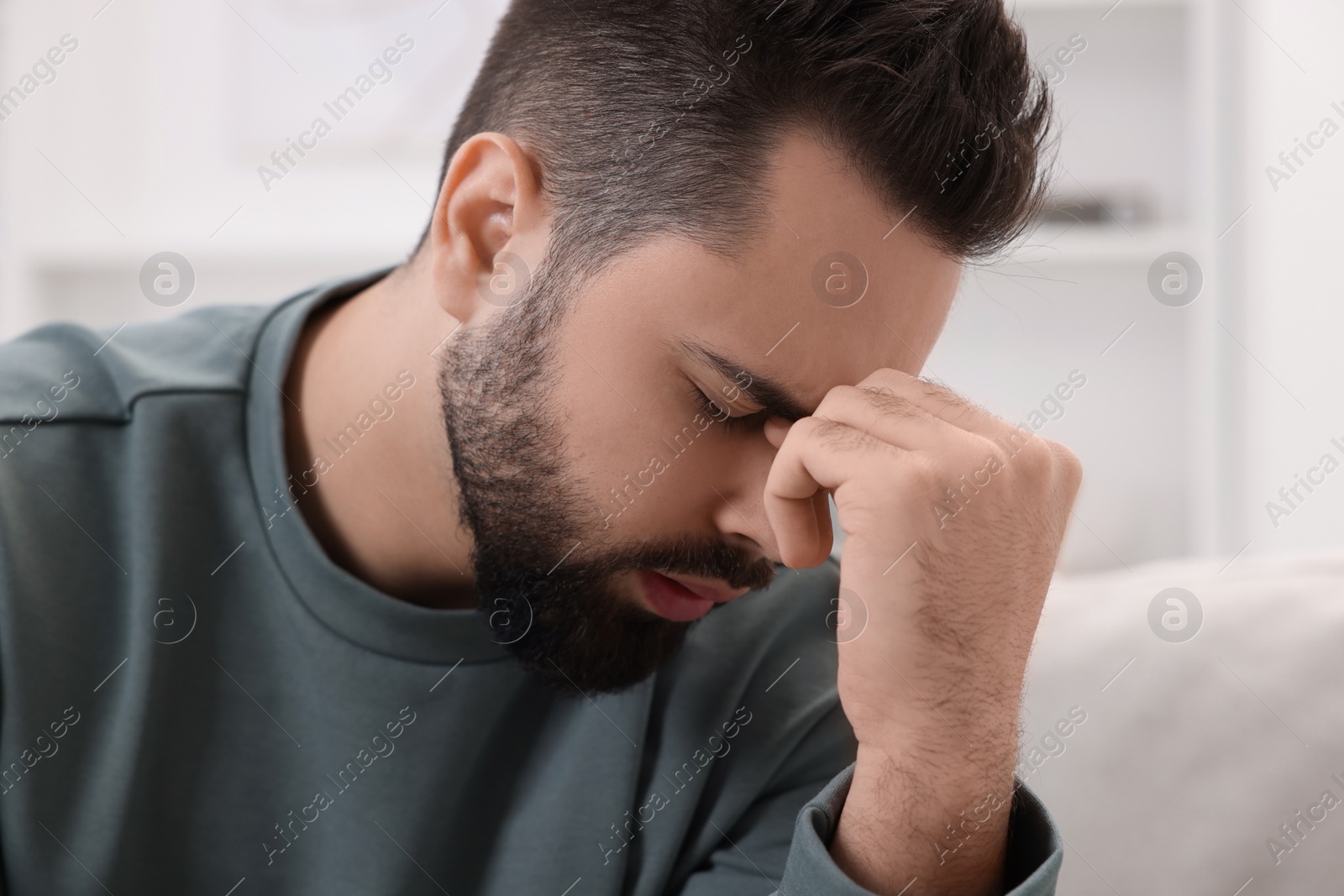 Photo of Man suffering from headache at home, closeup