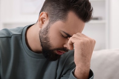 Photo of Man suffering from headache at home, closeup