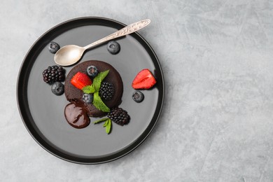 Plate with delicious chocolate fondant, berries and mint on grey table, top view. Space for text