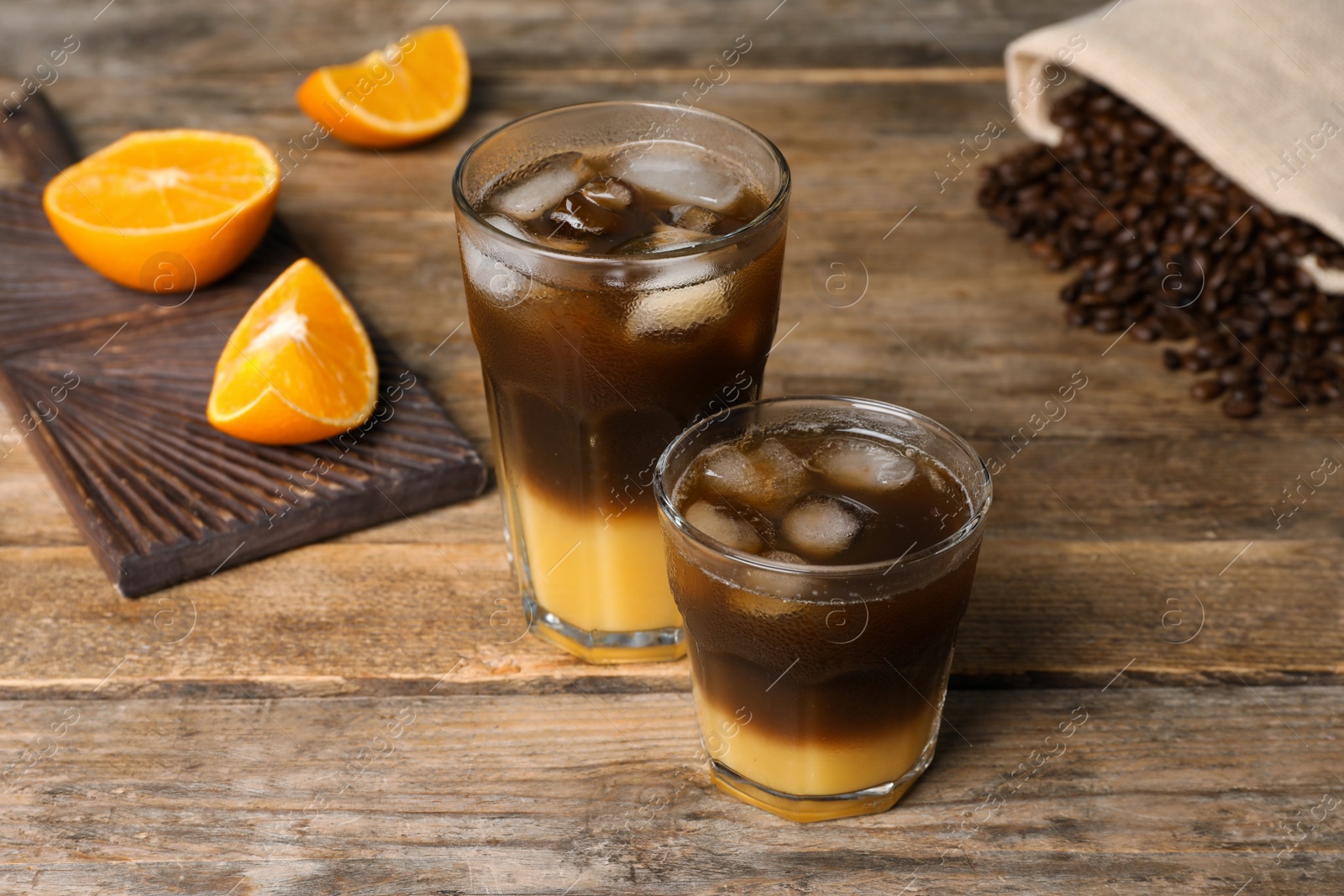 Photo of Tasty refreshing drink with coffee and orange juice on wooden table